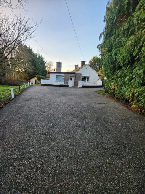 Clean gravel driveway with green hedges after professional cleaning